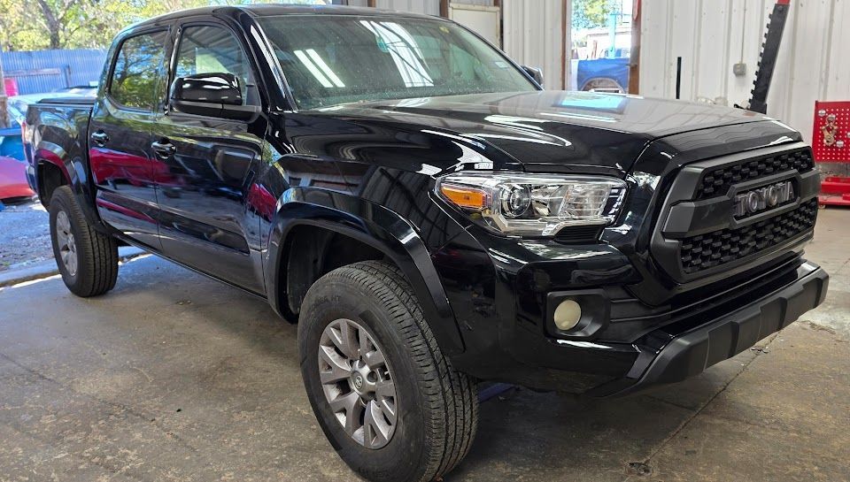 Black Toyota Tacoma pickup truck parked inside a garage.