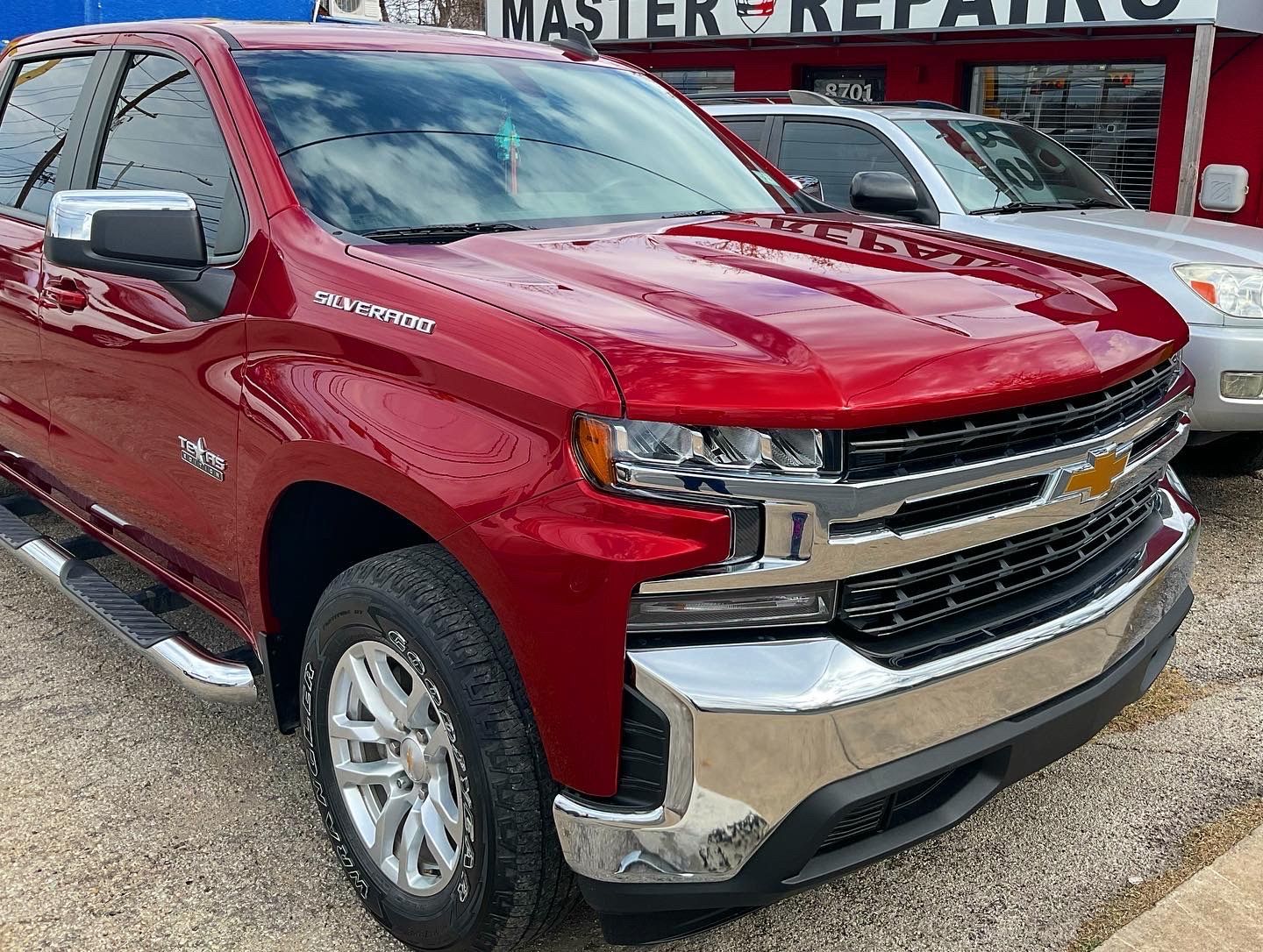 Red Chevrolet Silverado pickup truck parked outside a repair shop.
