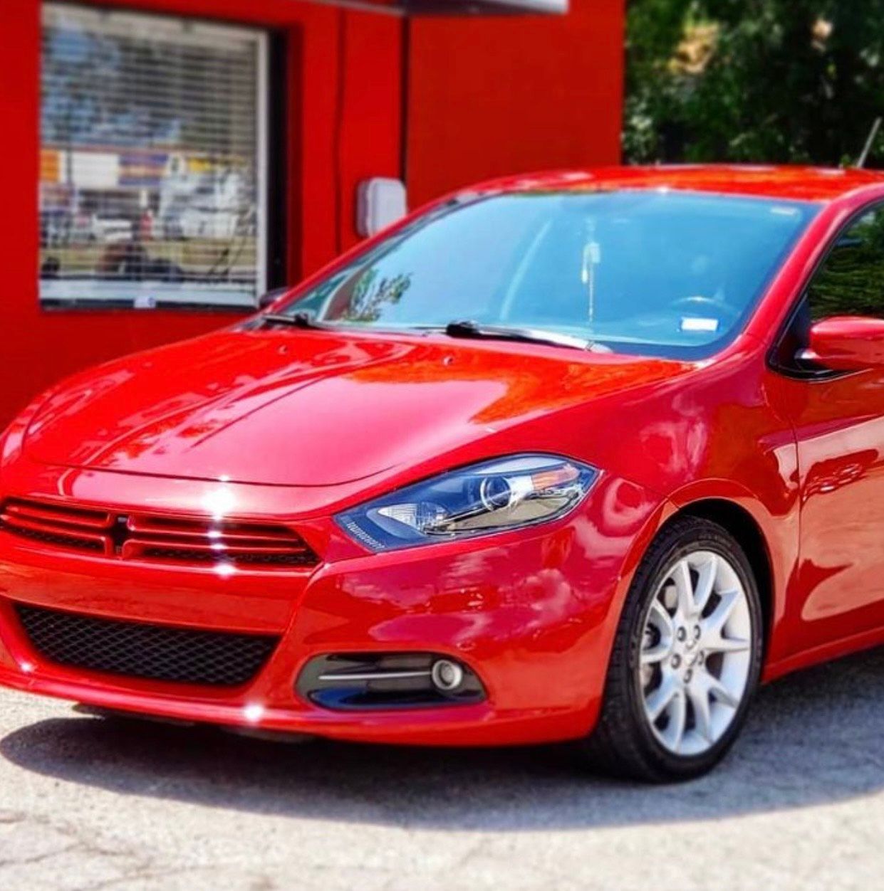 Red Dodge Dart parked outside a red building.