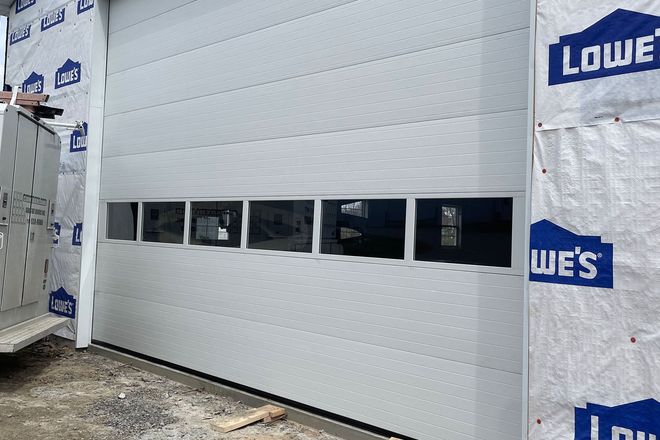 A grey, modern garage door with a row of five horizontal windows.