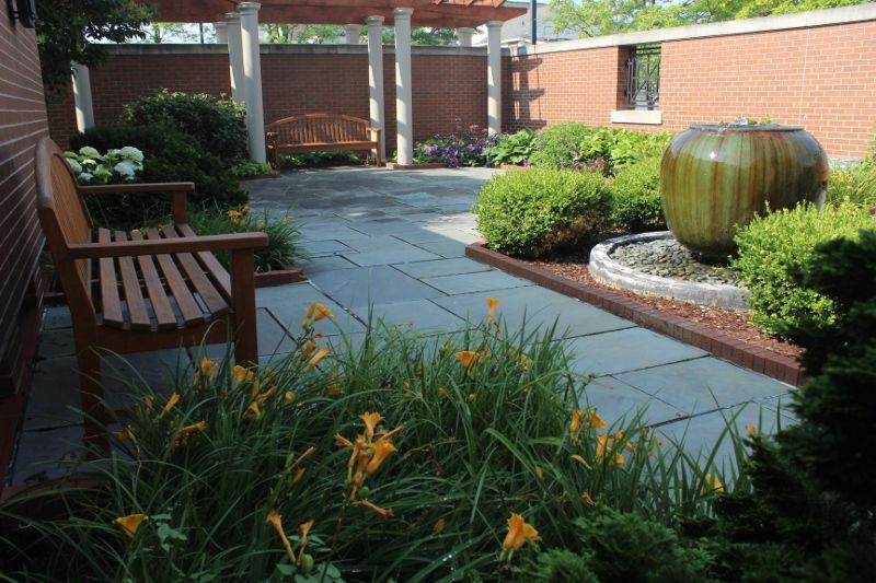 There is a bench and a fountain in the garden.