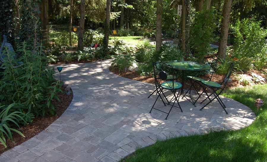 A patio with a table and chairs in the middle of a forest.