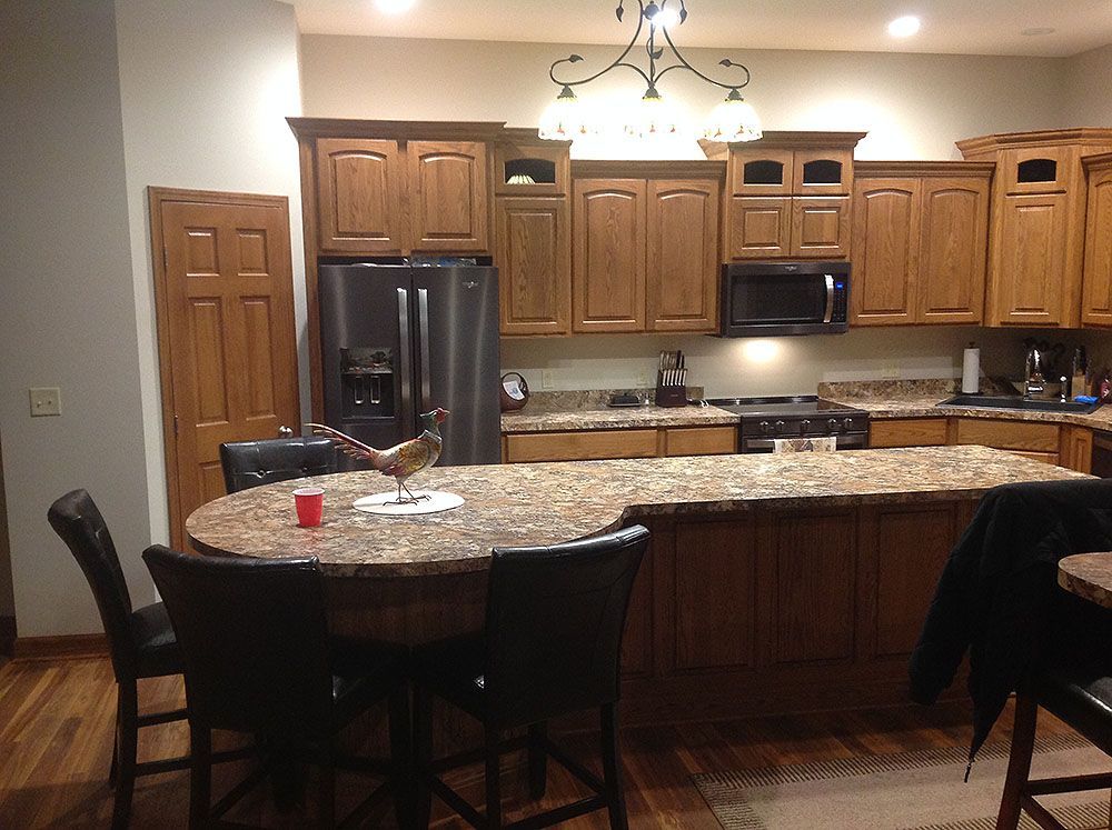 Kitchen with wooden cabinets, island, and bar stools; stainless steel appliances.