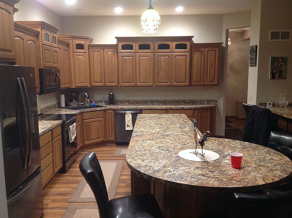 Kitchen with oak cabinets, granite countertops, island, and black appliances.