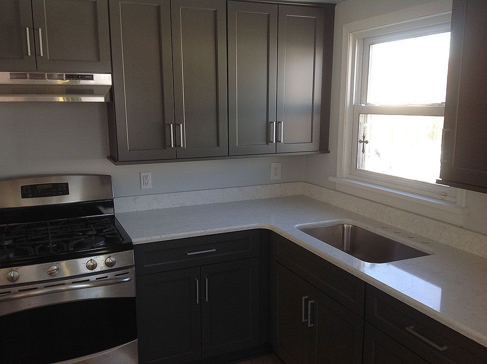 Kitchen with gray cabinets, white countertops, stainless steel appliances, and a window.