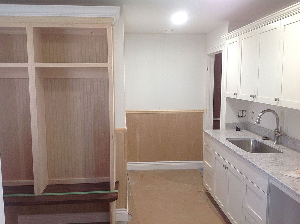 Mudroom with unfinished built-in storage, white cabinets, and a sink area; neutral color palette.