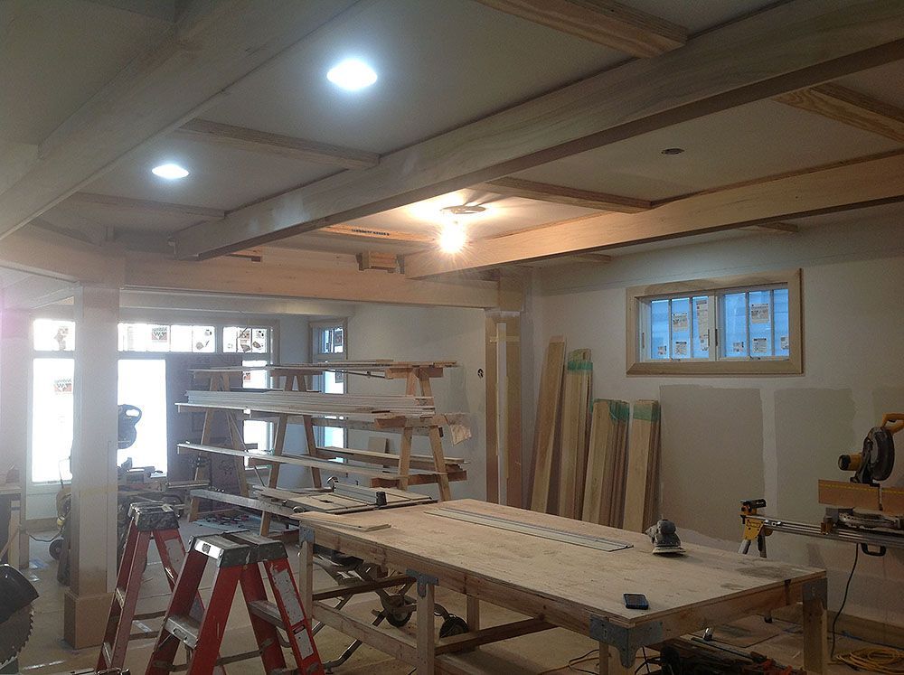 Workshop interior with woodworking table, shelves, beams, and lumber.