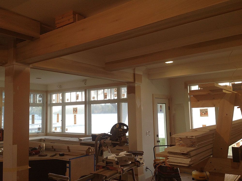Interior of a house underconstruction; wooden beams and pillars, windows, stairs, and tools visible.