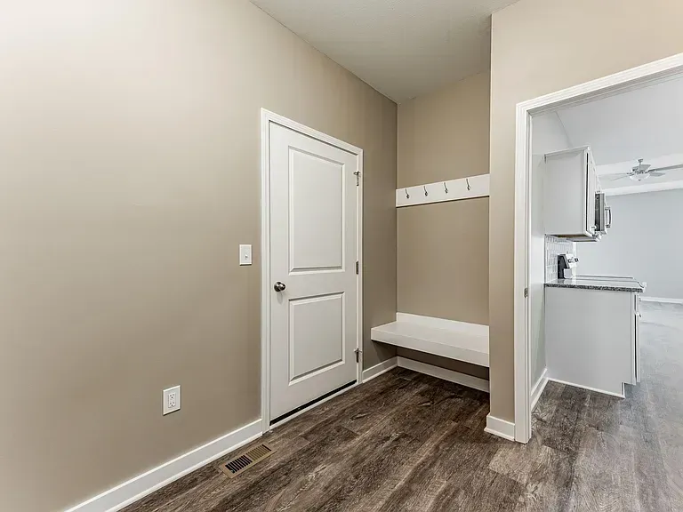 There is a bench in the hallway next to the door.