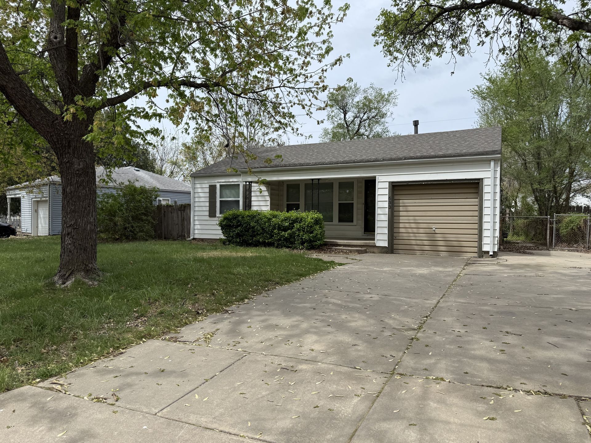 A white house with a garage and a tree in front of it