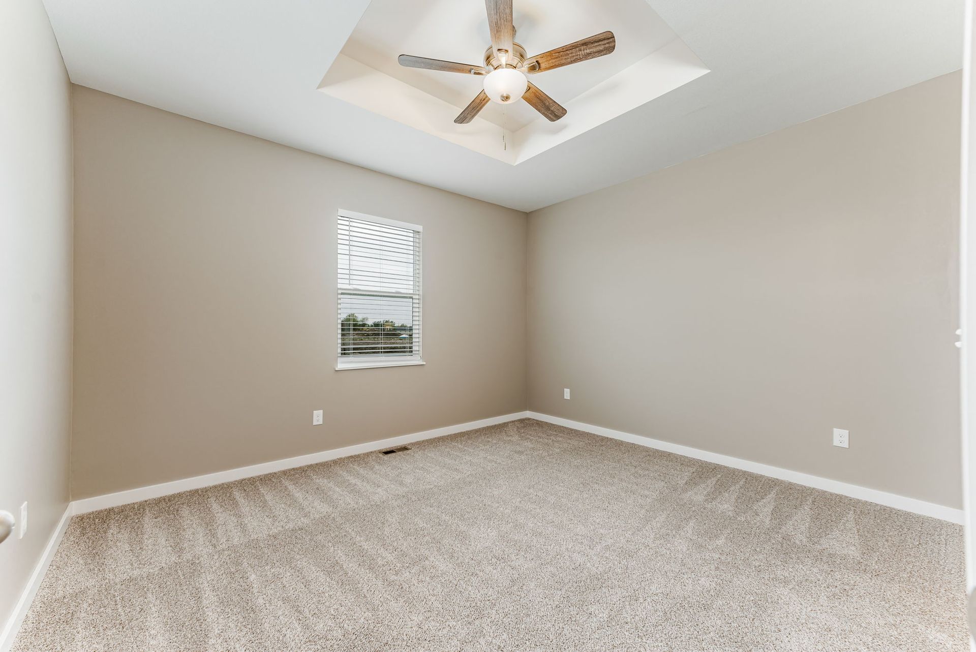 An empty bedroom with a ceiling fan and a window.