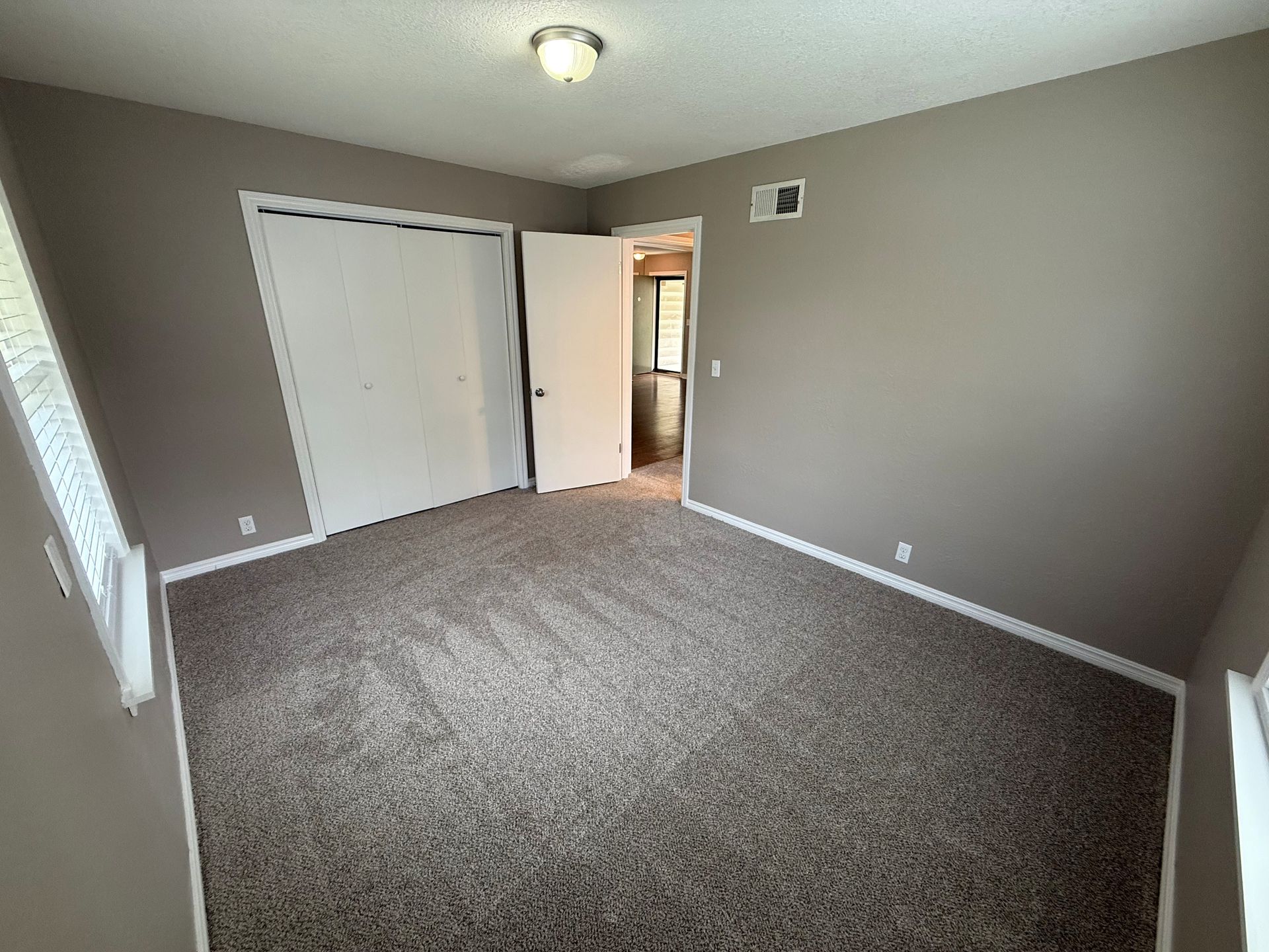 An empty bedroom with a carpeted floor and a closet.