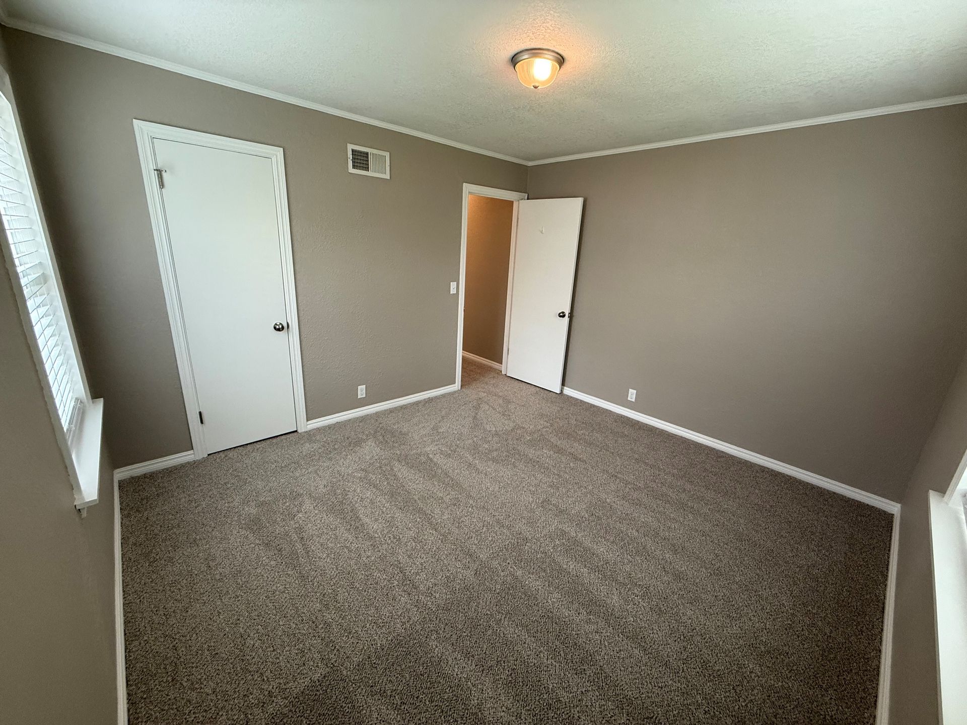 An empty bedroom with a carpeted floor and a door.