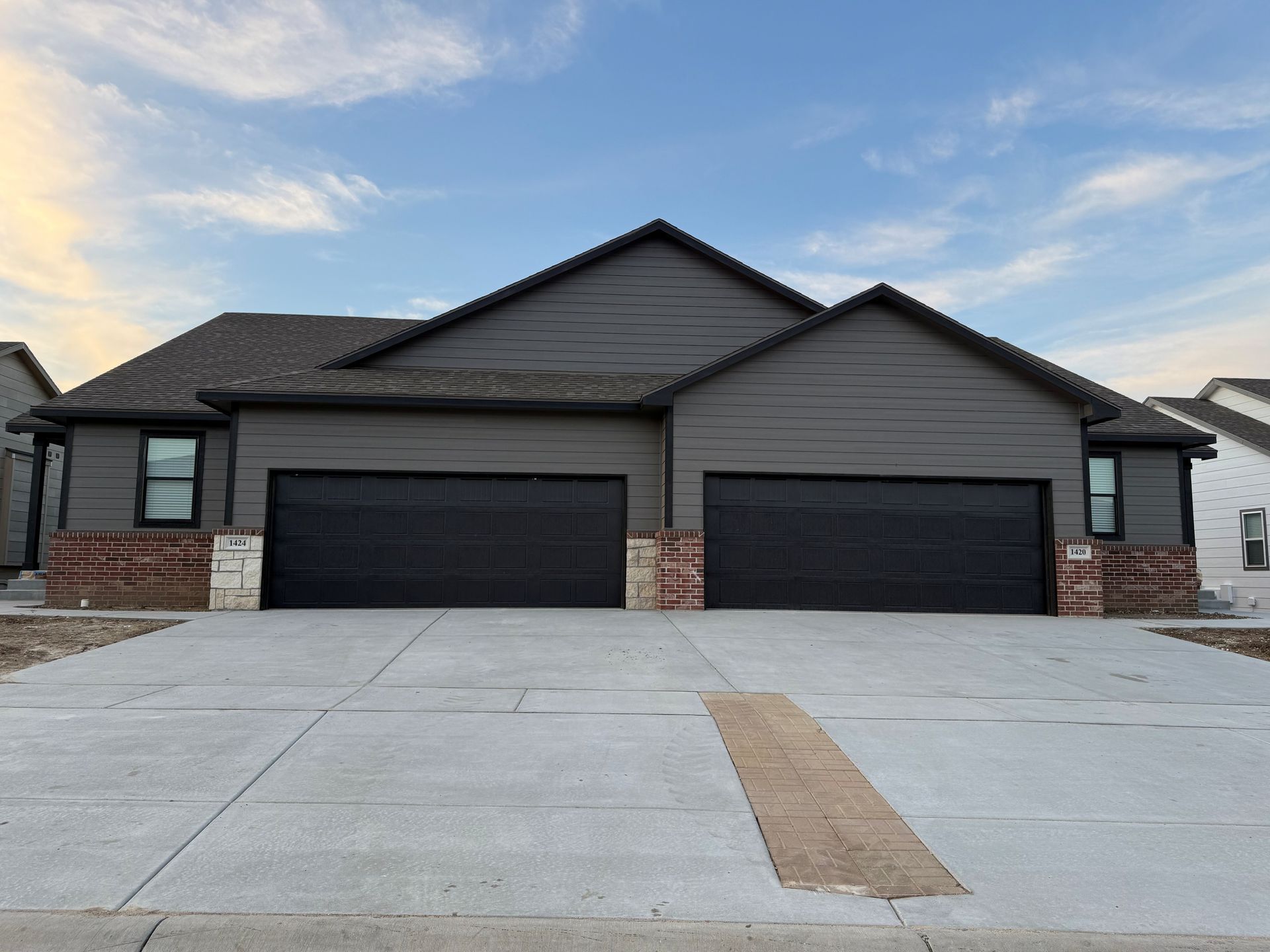 A house with two garage doors and a concrete driveway in front of it.