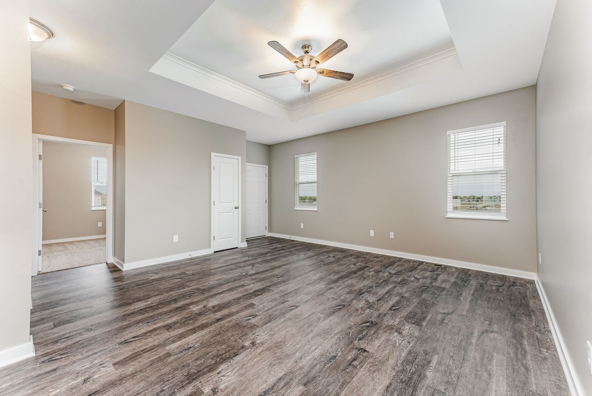 An empty living room with hardwood floors and a ceiling fan.