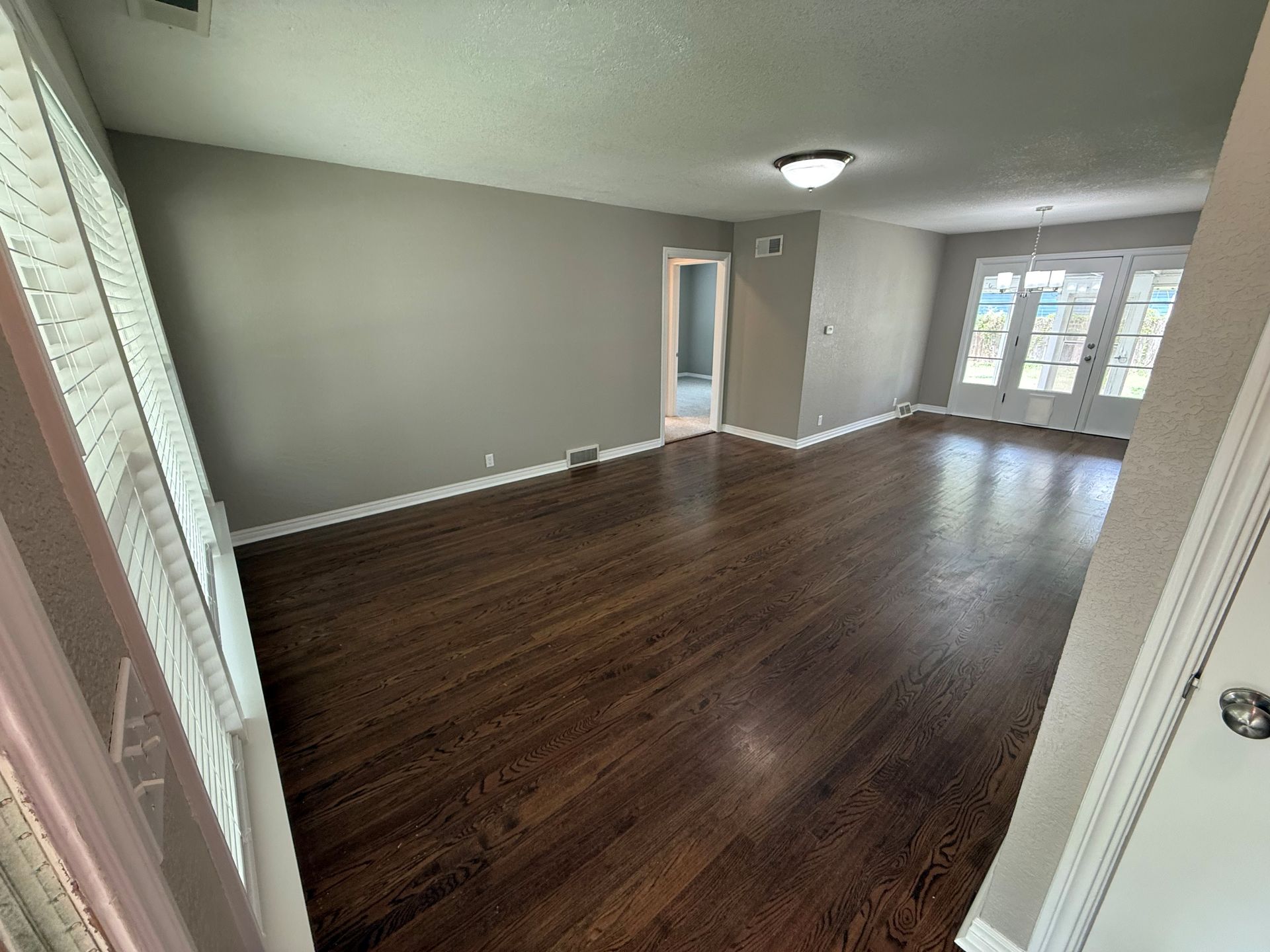 An empty living room with hardwood floors and gray walls.