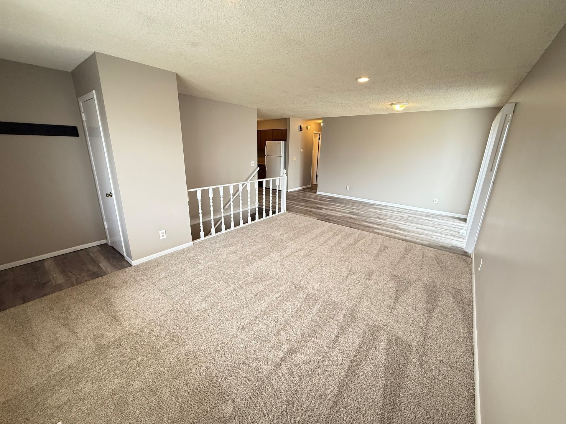 An empty living room with a staircase leading to the second floor.