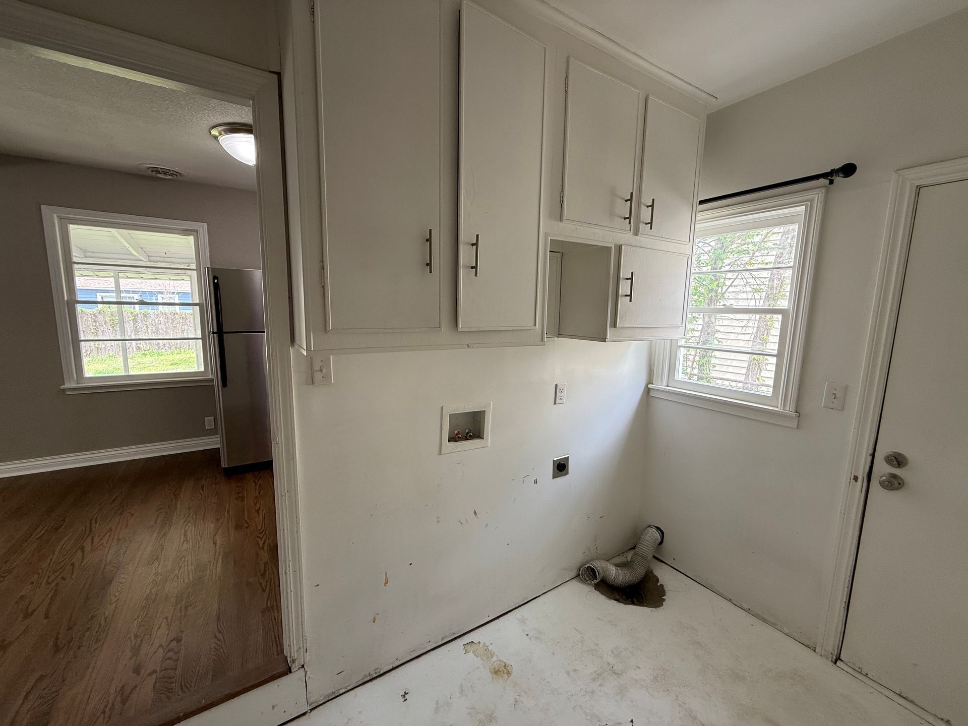 A kitchen with white cabinets , a refrigerator , and a window.