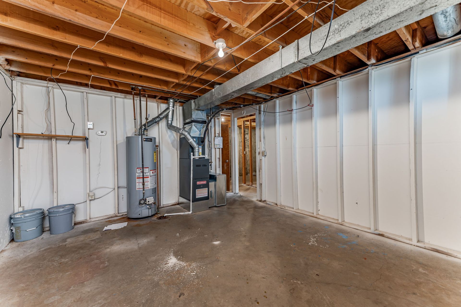 An empty basement with a water heater and a furnace.