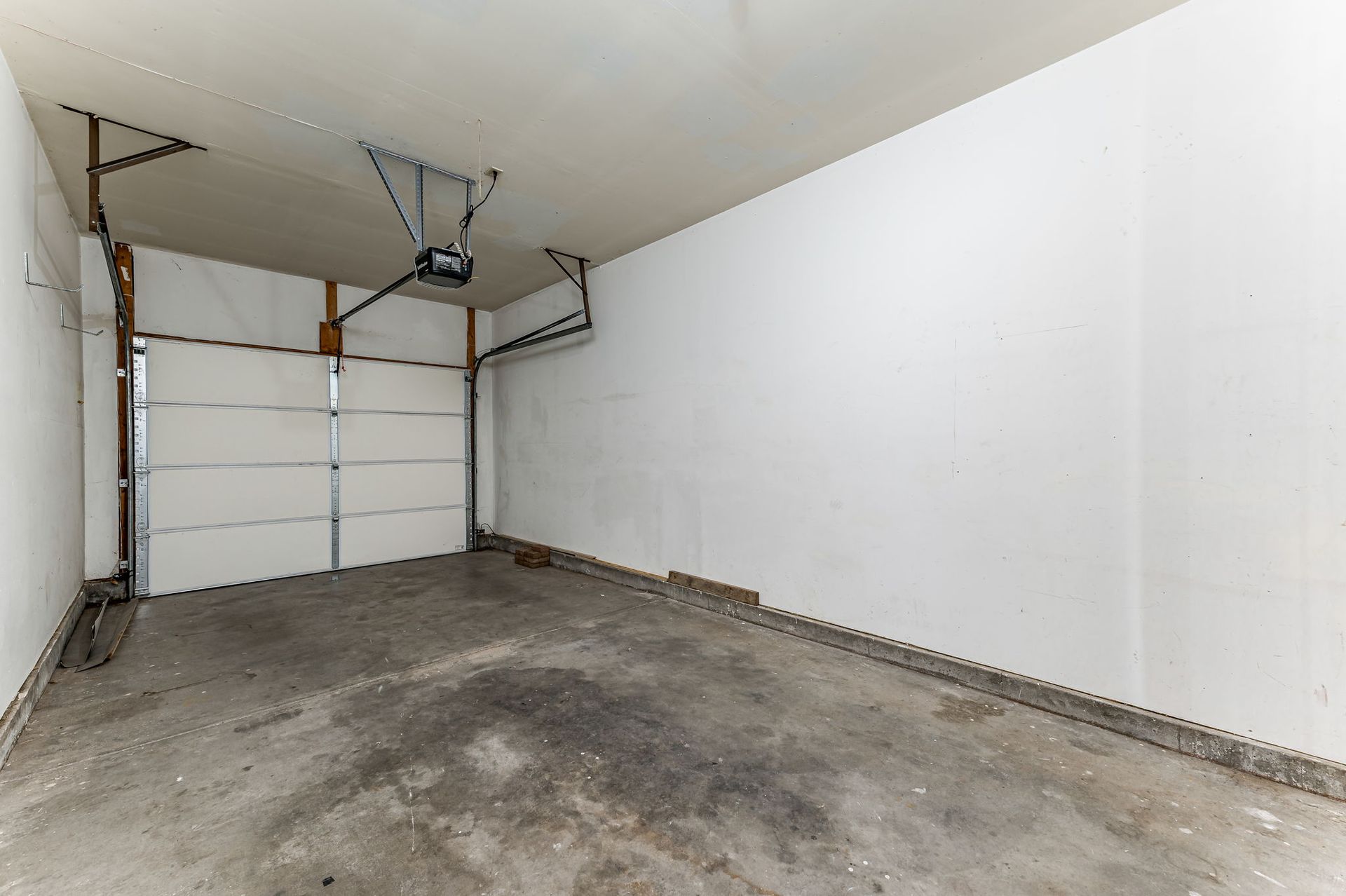 An empty garage with a garage door open and a ceiling fan.