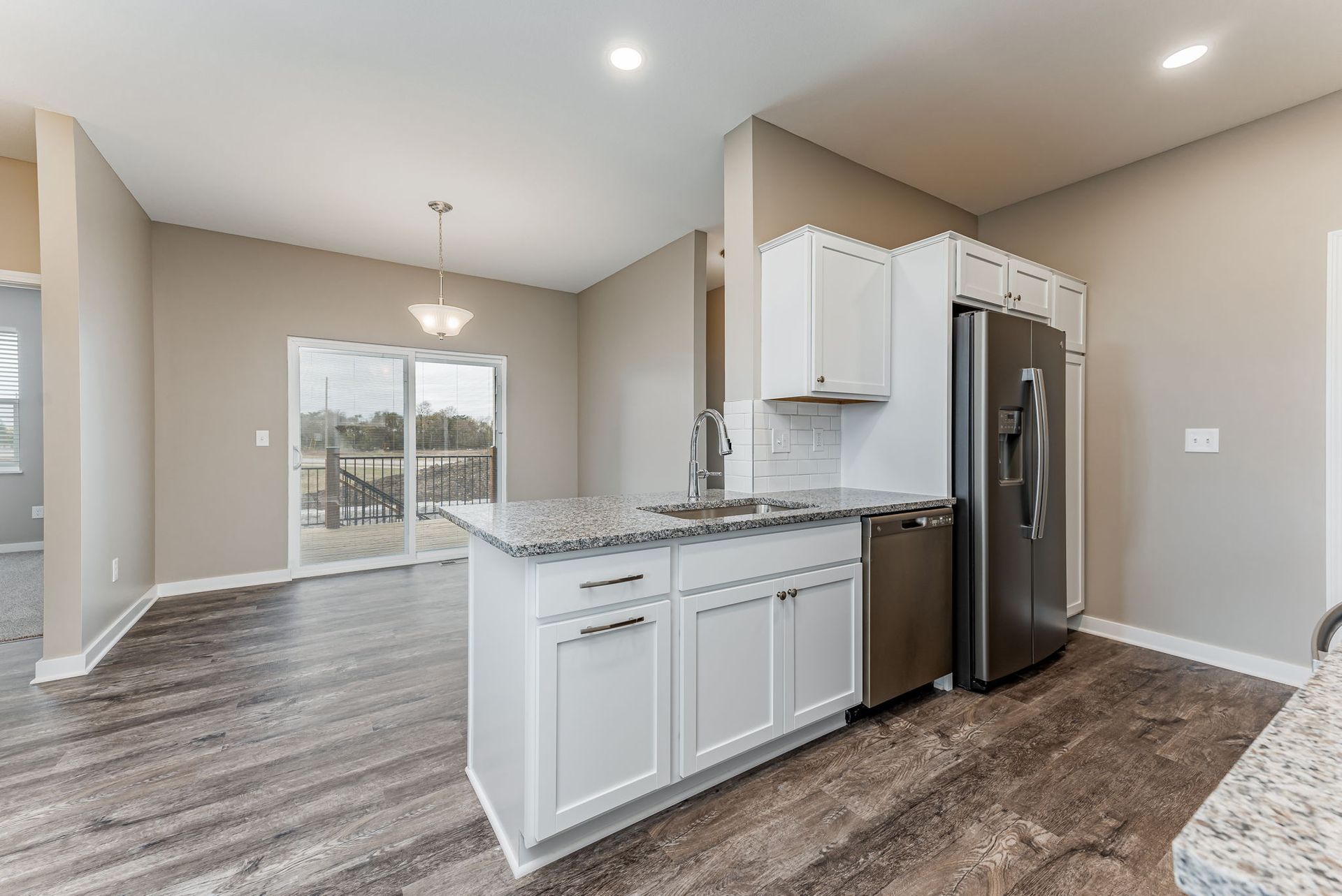 A kitchen with white cabinets , granite counter tops , stainless steel appliances and a refrigerator.
