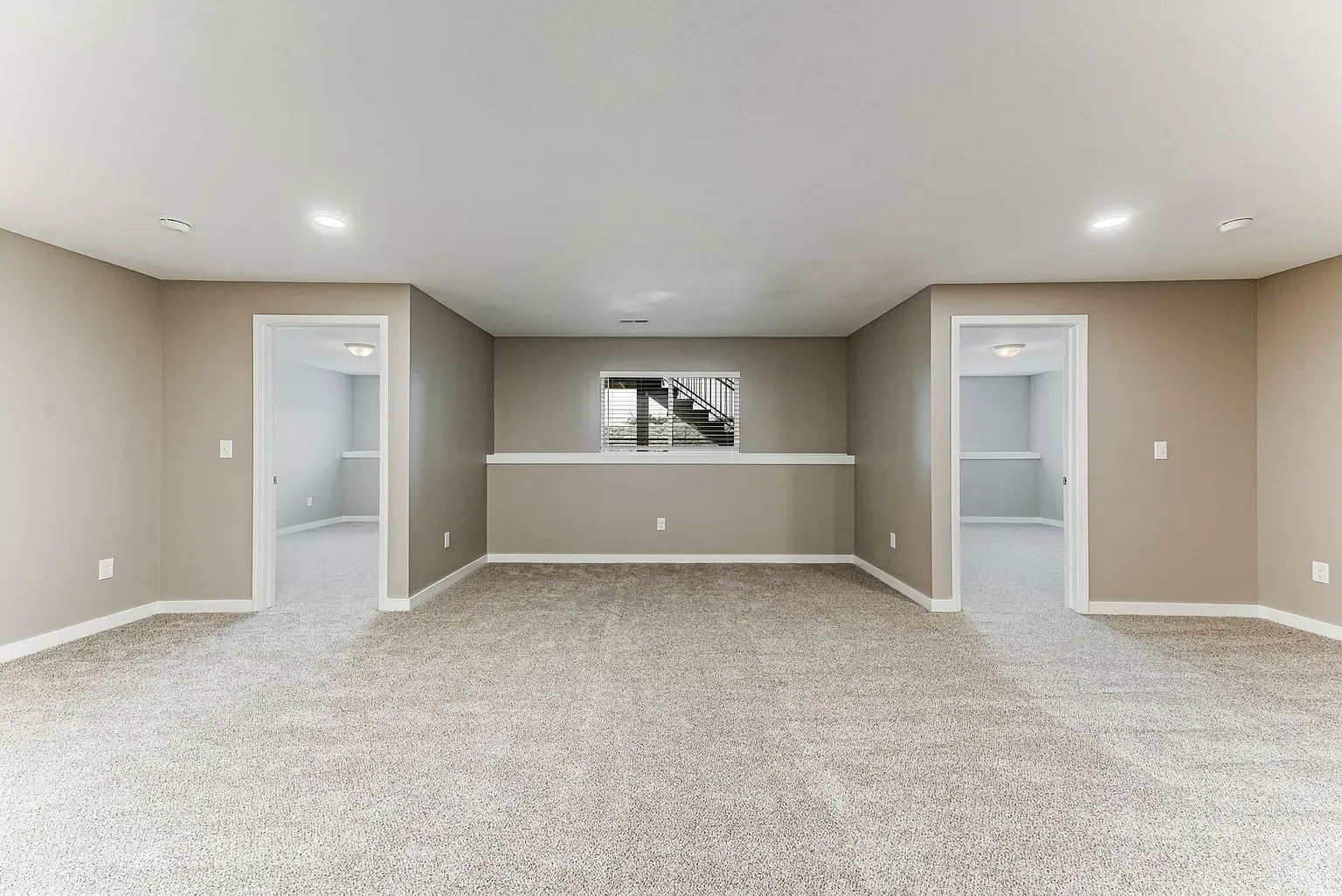 An empty basement with a carpeted floor and a painting on the wall.