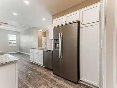 A kitchen with white cabinets and a stainless steel refrigerator.