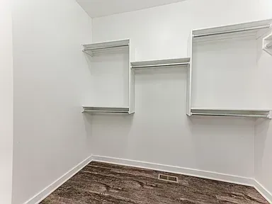 An empty walk in closet with a carpeted floor and shelves.