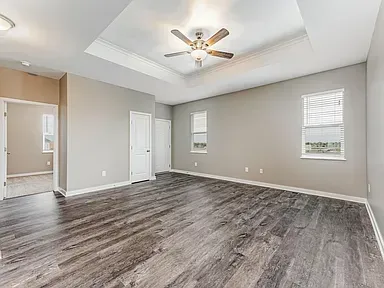 An empty living room with hardwood floors and a ceiling fan.