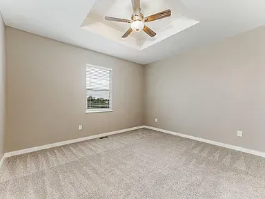 An empty bedroom with a ceiling fan and a window.