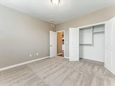 An empty bedroom with a carpeted floor and a closet.