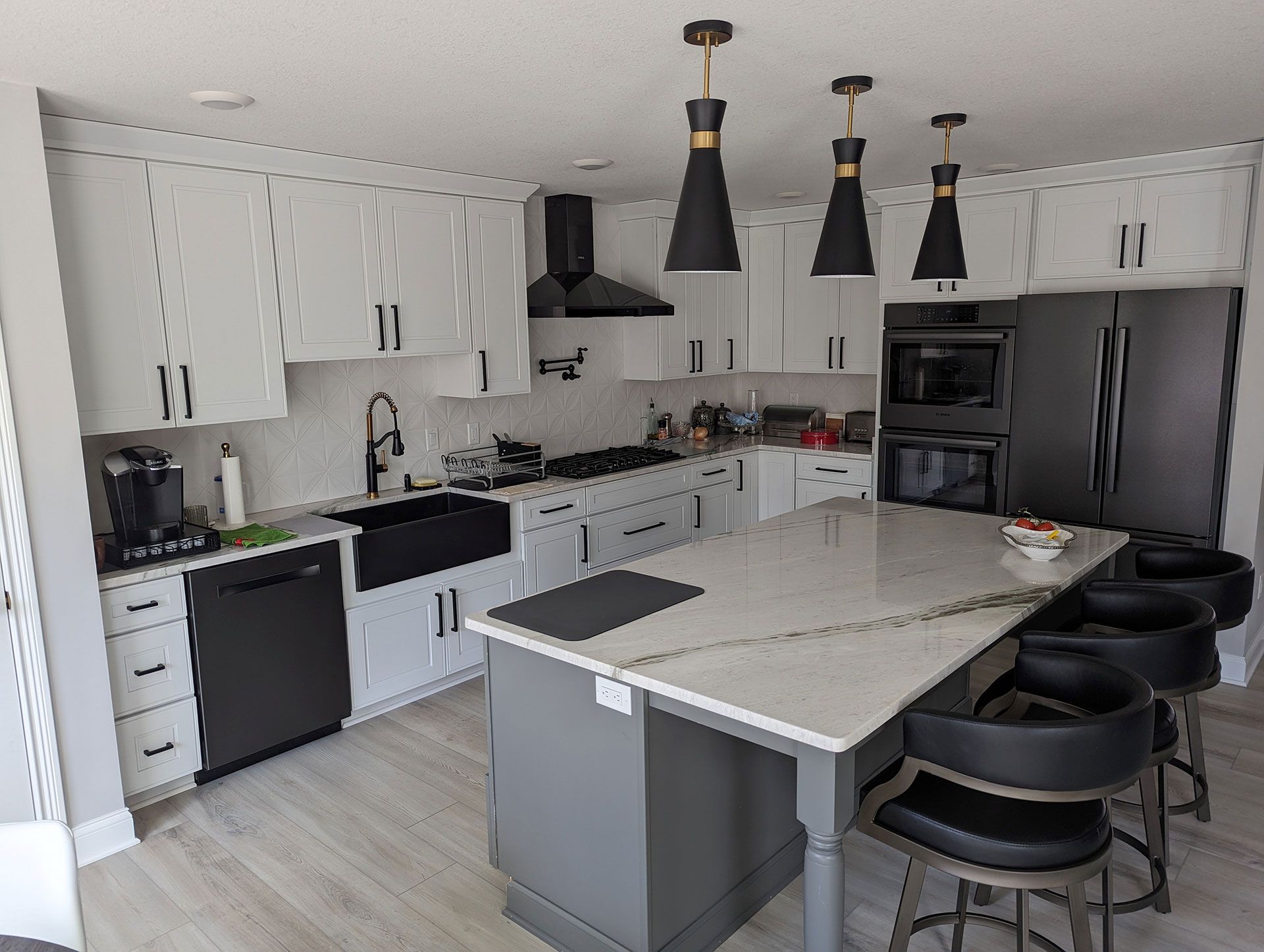 kitchen with white cabinets, black appliances, and a large island.