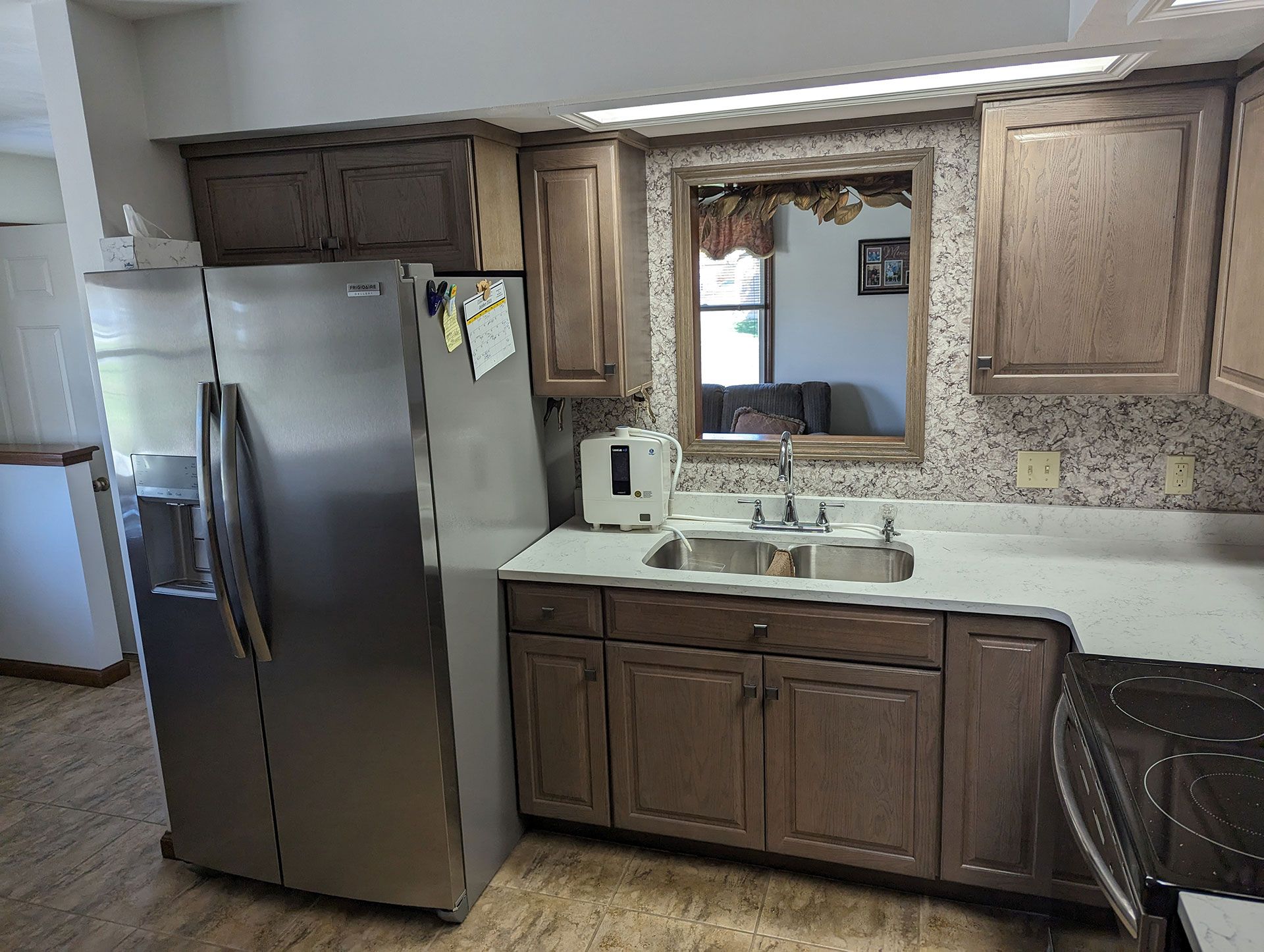 wooden cabinets in the kitchen with stainless steel appliances, a sink, and a refrigerator