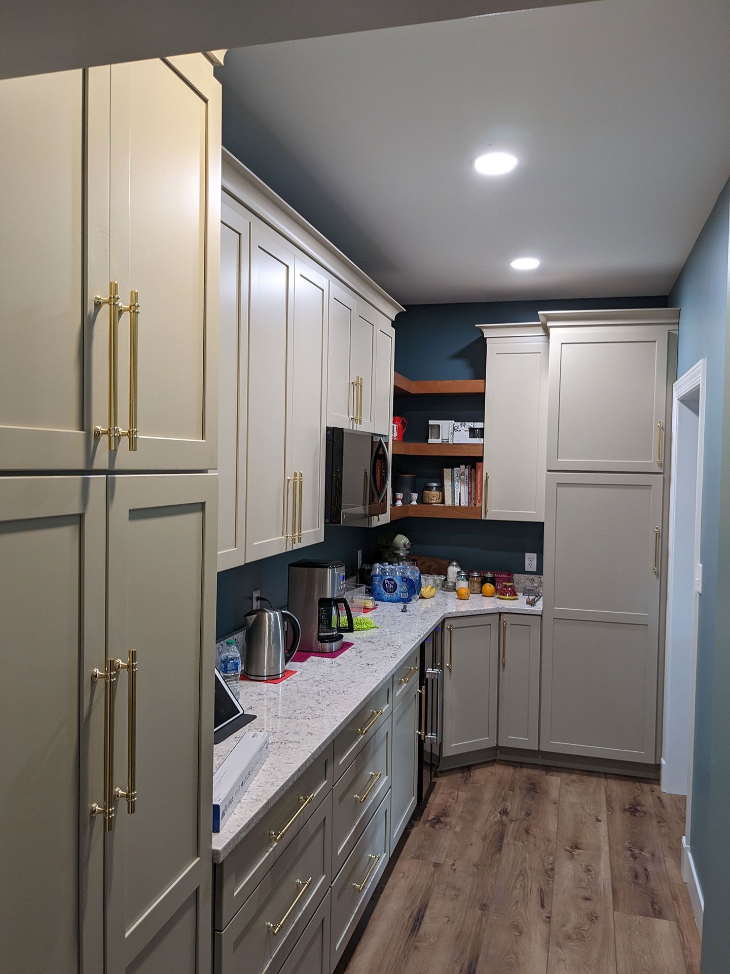 A kitchen with white cabinets and wooden floors