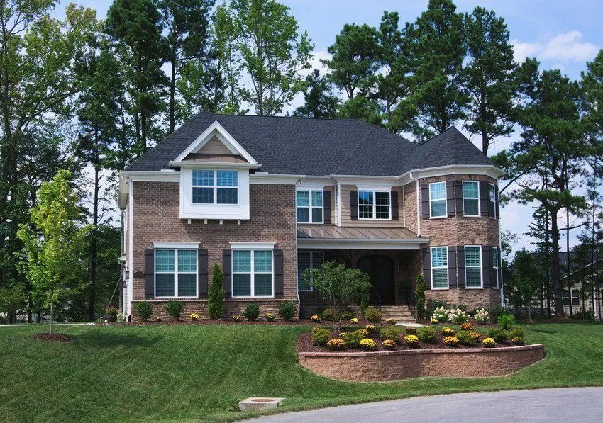 A large brick house with a black roof and white shutters