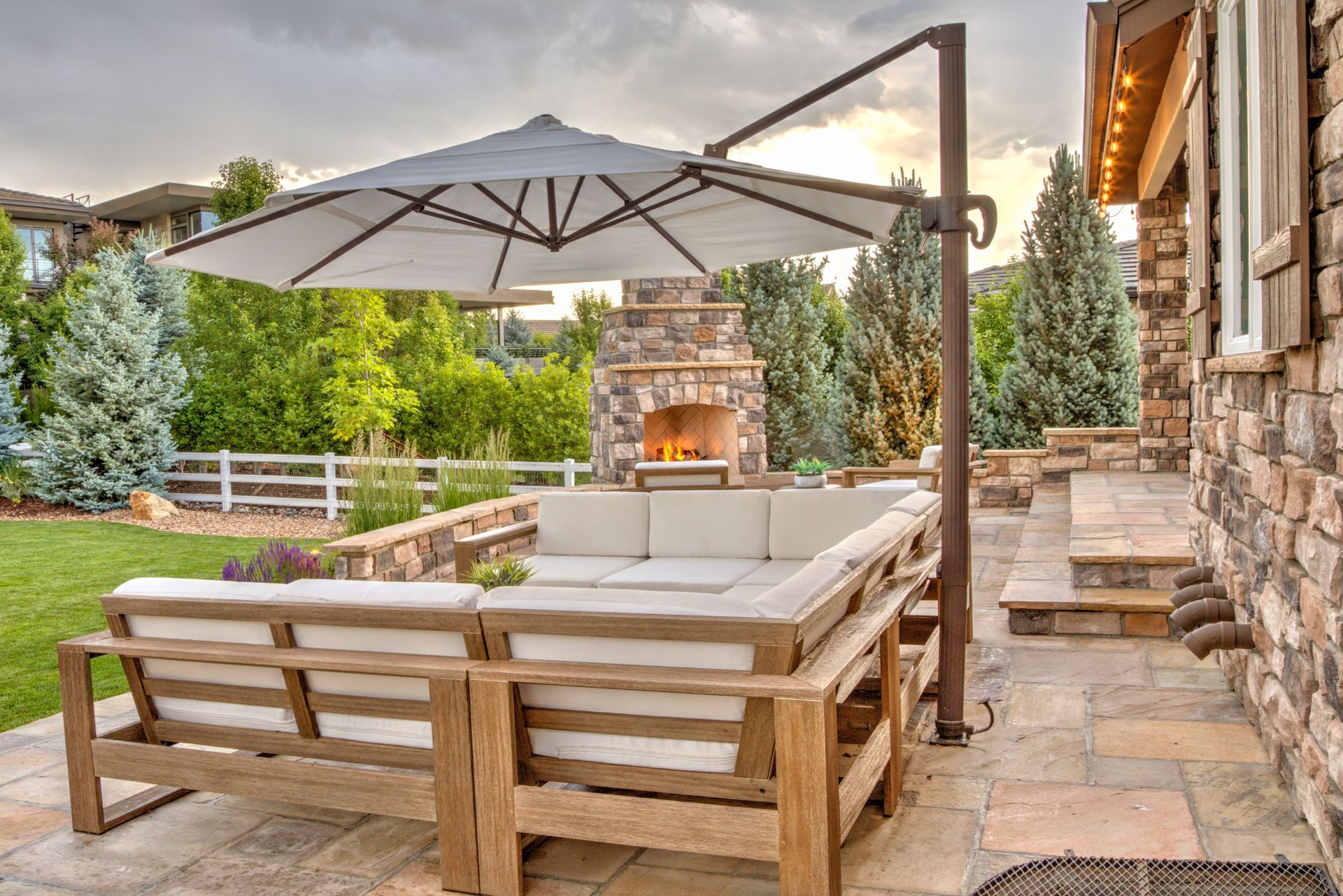 Outdoor patio with sectional sofa, fireplace, and cantilevered umbrella.