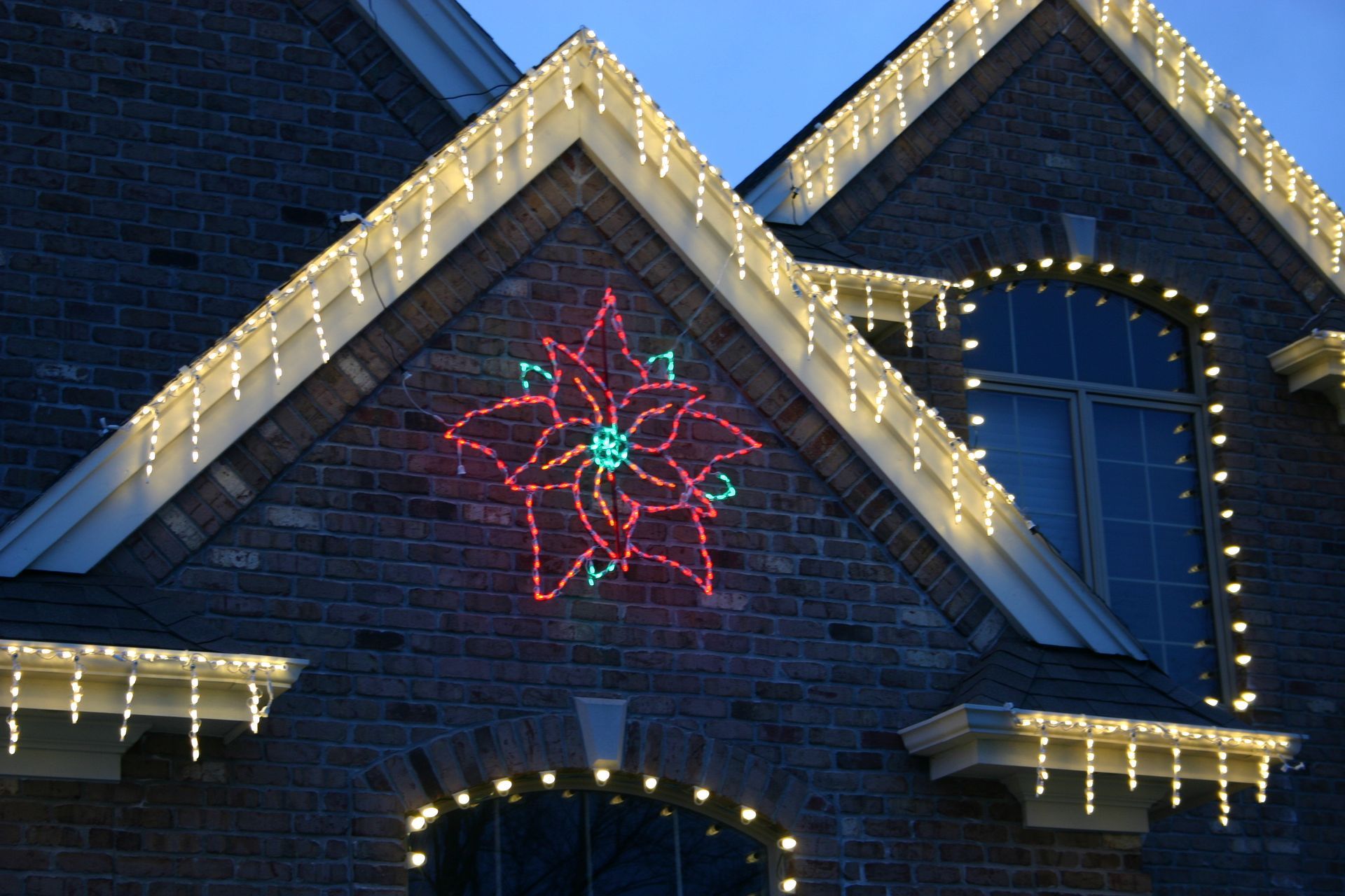 House decorated with Christmas lights, including a poinsettia display.