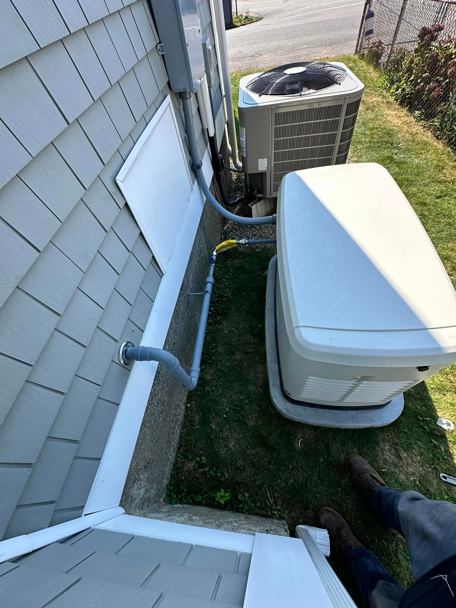 A person is standing in front of a house next to a generator.