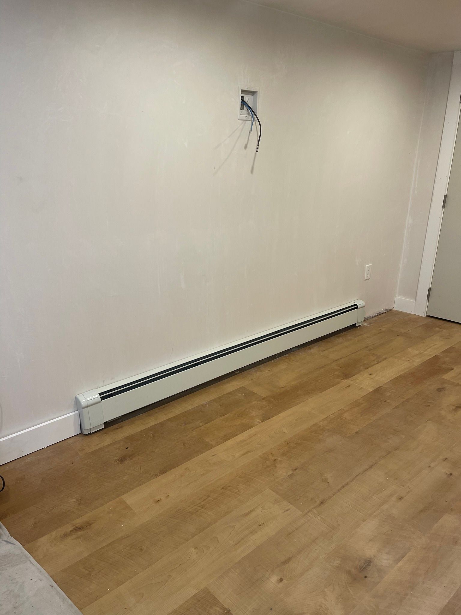A room with hardwood floors and a white radiator on the wall.