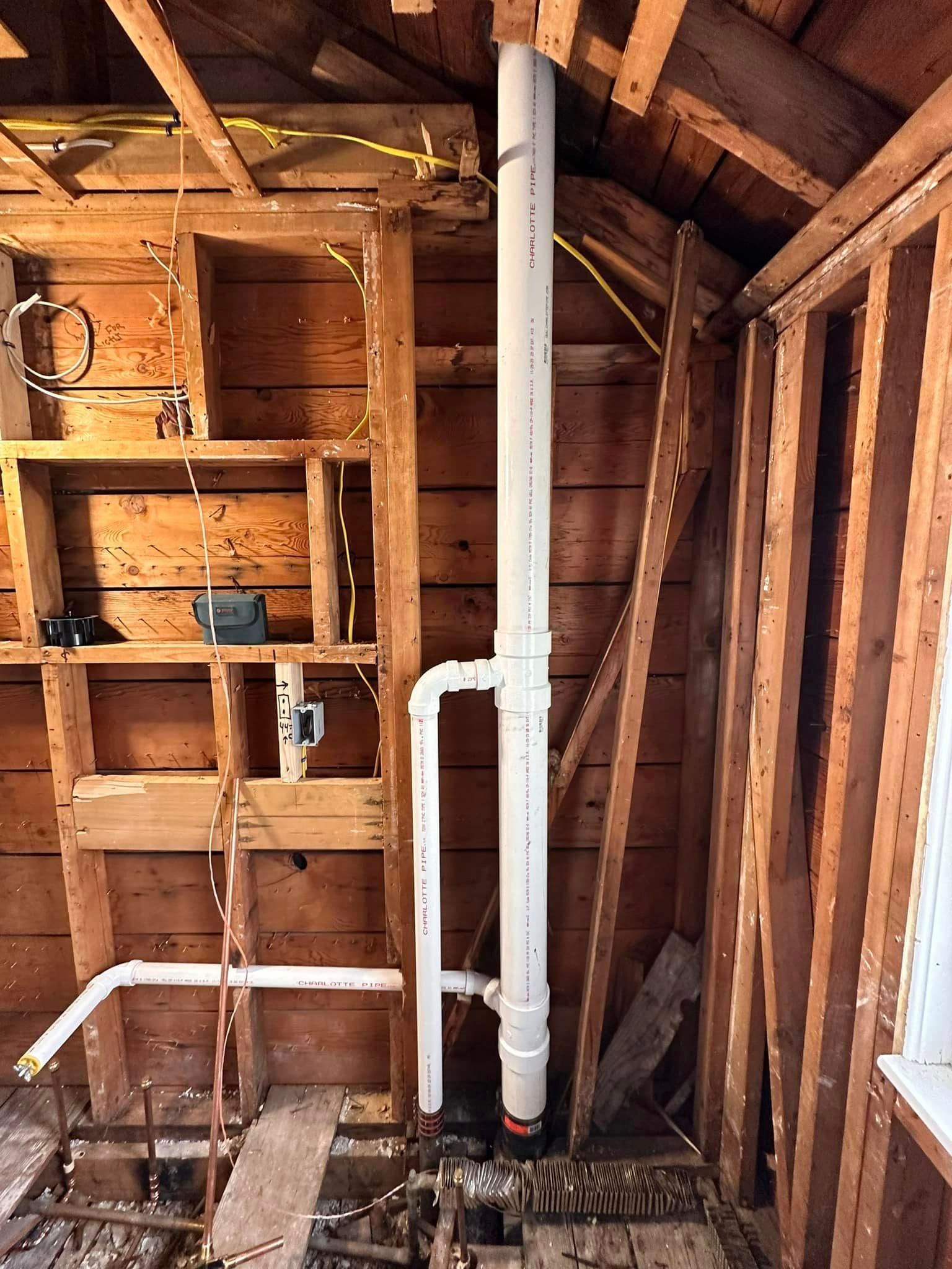 A bathroom under construction with a pipe coming out of the ceiling.