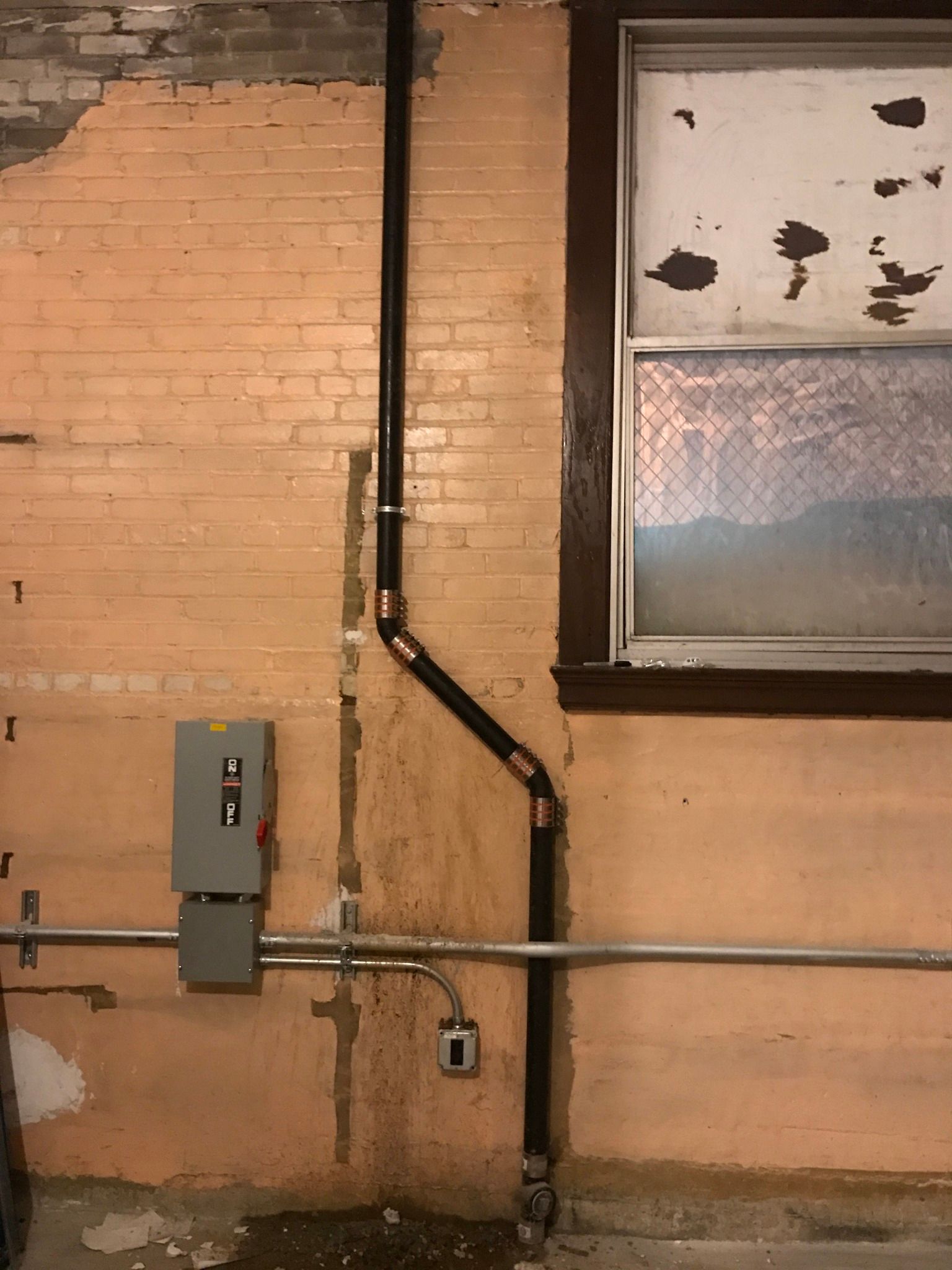 A brick wall with a window and a pipe on it