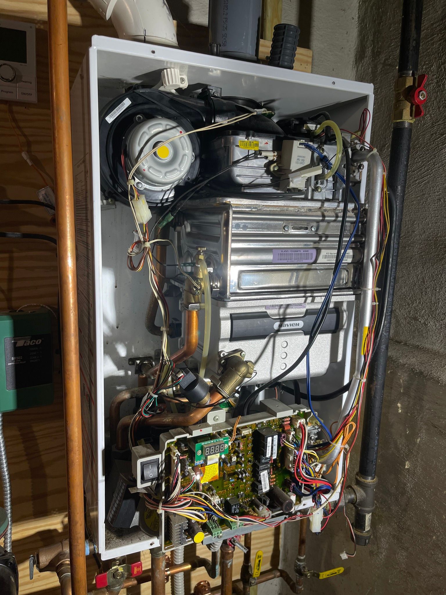 The inside of a water heater with a lot of wires coming out of it.