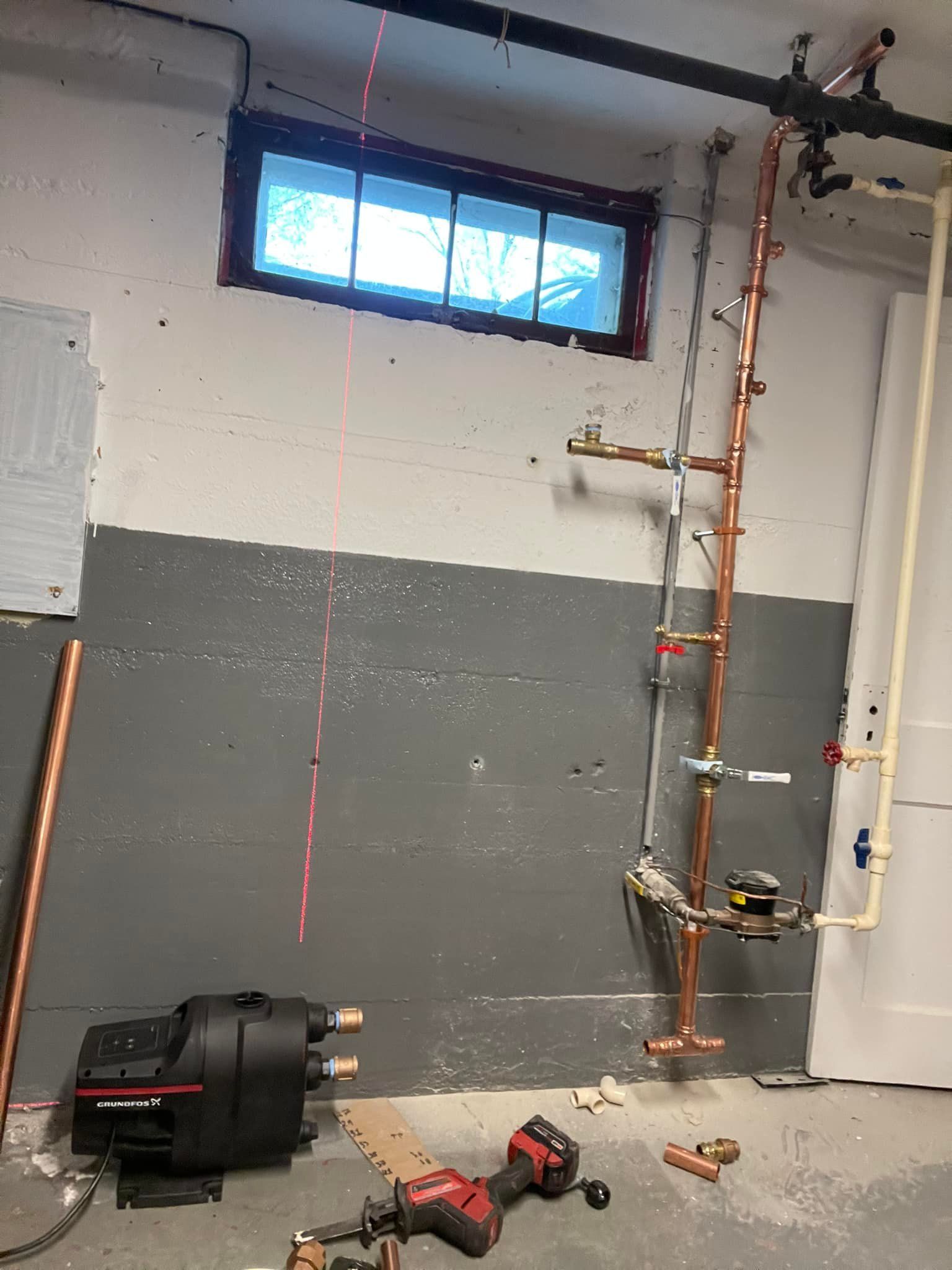 A room with a lot of pipes and a window.