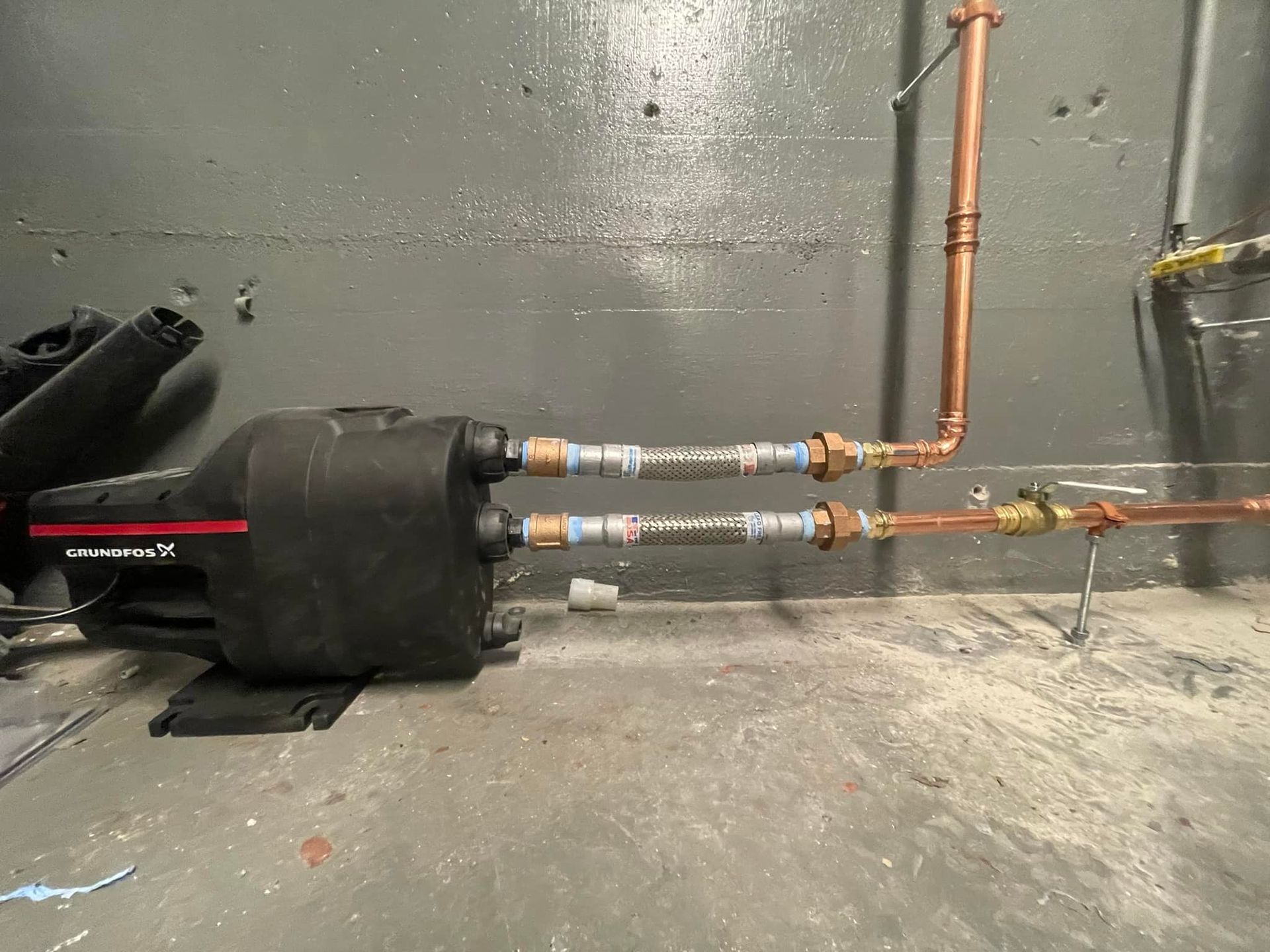 A copper pipe is connected to a black device in a room.