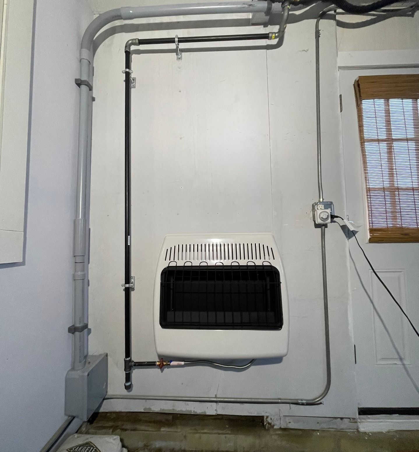 A white heater is mounted on a wall next to a window