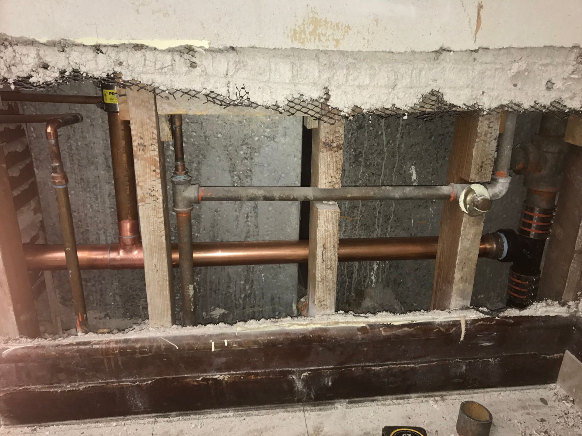 A hole in a wall with copper pipes coming out of it