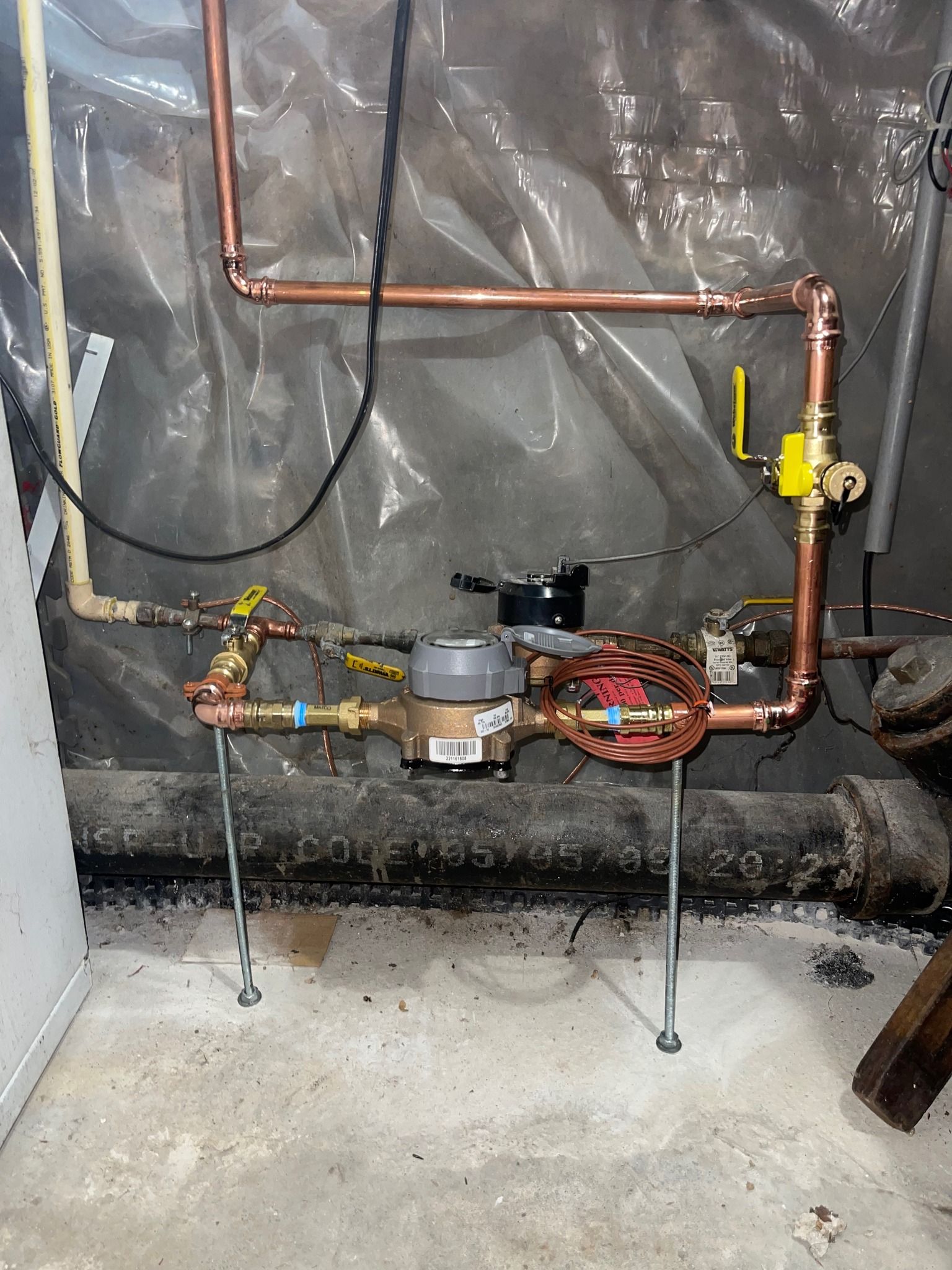 A copper pipe with a water meter attached to it in a basement.