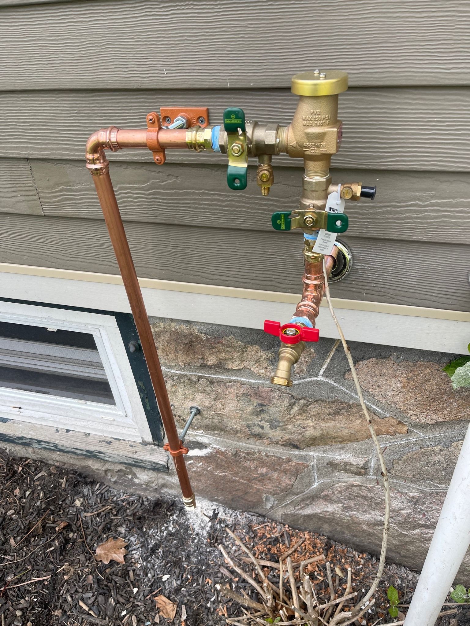 A copper pipe is attached to the side of a house.