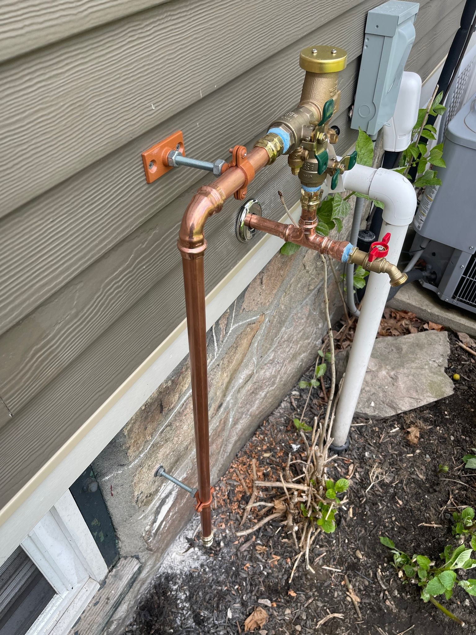 A copper pipe is attached to the side of a house.