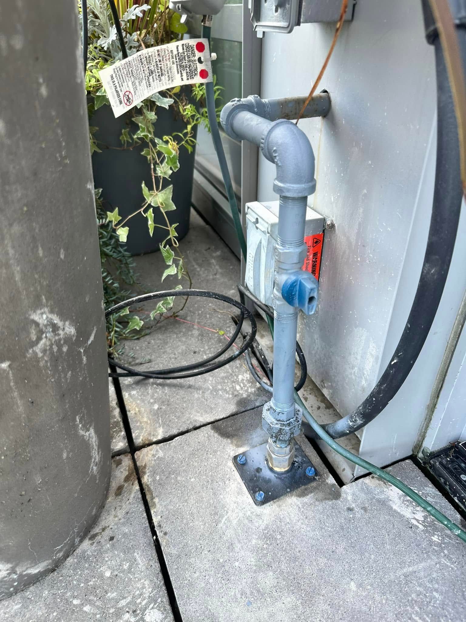 A hose is attached to a pipe on the side of a building.